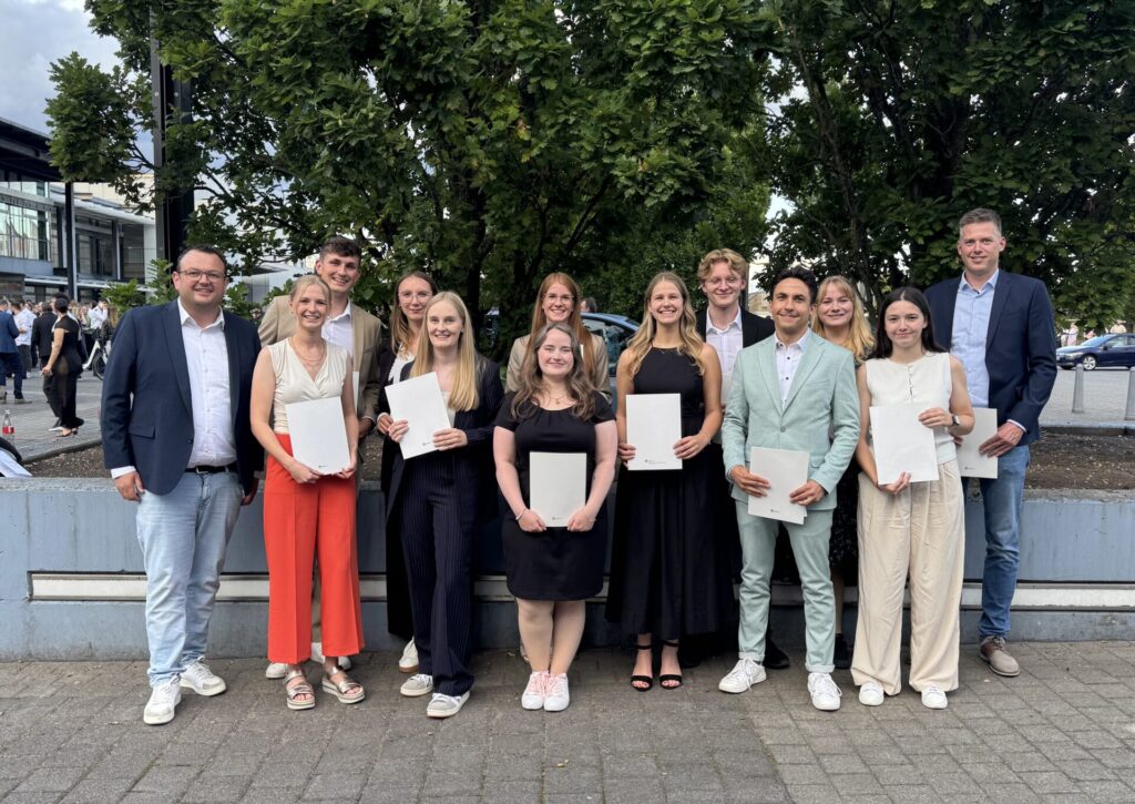 14 duale Studentinnen und Studenten schlossen jetzt erfolgreich ihr Studium ab. Auf dem Foto zu sehen: Ausbildungsleiter Christof Kleinwege (li.) mit den Bachelor of Laws-Studierenden bei der Graduierungsfeier.