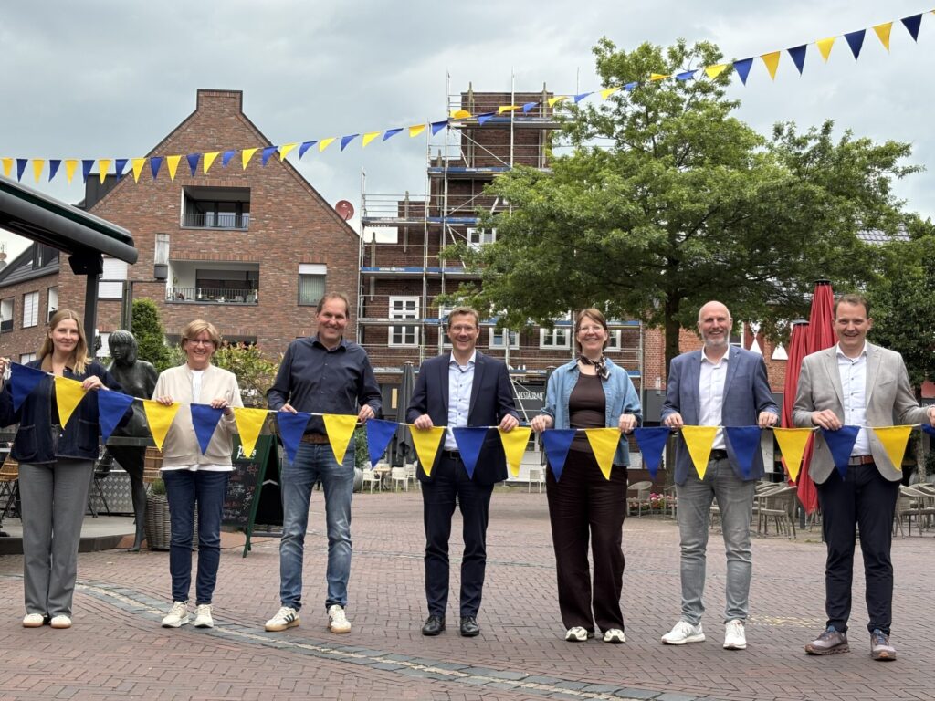 Gemeinsam für eine attraktive Innenstadt: Die Sponsoren präsentieren die neuen Wimpel, die das Stadtbild verschönern (vlnr.): Karina Woźniak-Arends (Stadtmarketing), Margot Isfording (Papierfabrik Vreden GmbH), Thomas Hackfort (Matthews Engineering), Hendrik Pieper (Saueressig), Eva-Maria Imping (Vredener Wirtschaftsvereinigung), Markus Thesing (Vredener Wirtschaftsvereinigung), Bürgermeister Dr. Tom Tenostendarp (Stadt Vreden). Foto: Stadt Vreden