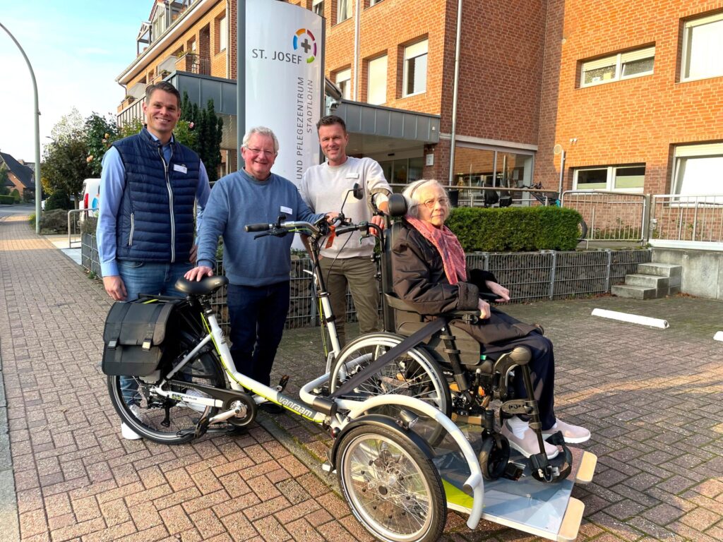 Neben den Mitarbeiterinnen und Mitarbeiter sowie den ehrenamtlichen Rollfietsenfahrern freuen sich vor allem die Bewohnerinnen und Bewohner des St. Josef Senioren- und Pflegezentrums Stadtlohn über die neue Rollfiets, die fortan auch den immobilen Seniorinnen und Senioren die Möglichkeiten einer Radtour bietet. Auf dem Foto zu sehen (v.l.n.r.): Philipp Naber, Ludwig Wübbelt (beide Einrichtungsleitung), Benjamin Nowak-Vazquez (Pflegedienstleiter) und Frau Engering (Bewohnerin). Foto: Pflegenetz Westmünsterland